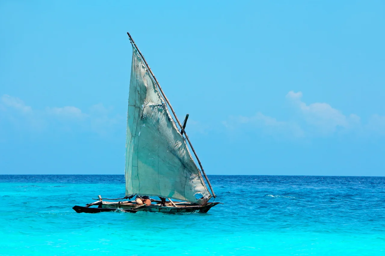 Dhow de vela tradicional navegando sobre las aguas turquesas de Zanzíbar