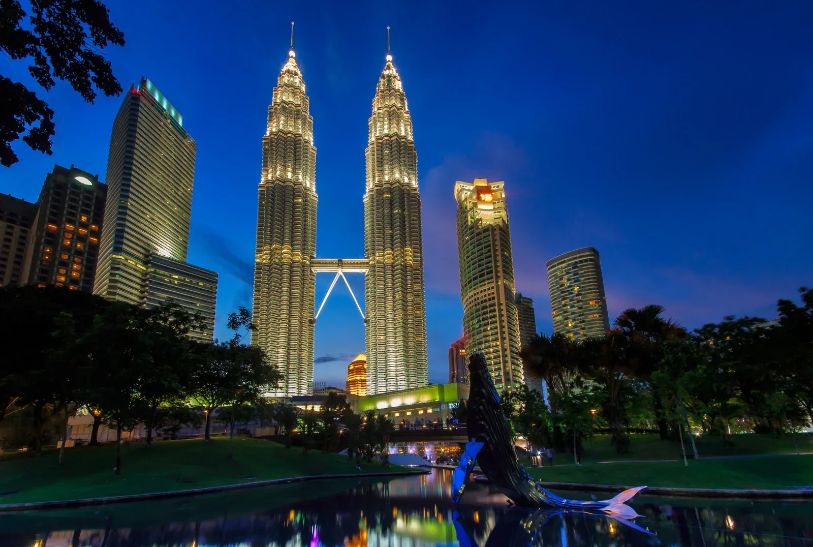 Torres Petronas iluminadas al anochecer sobre los jardines de KLCC en Kuala Lumpur, Malasia